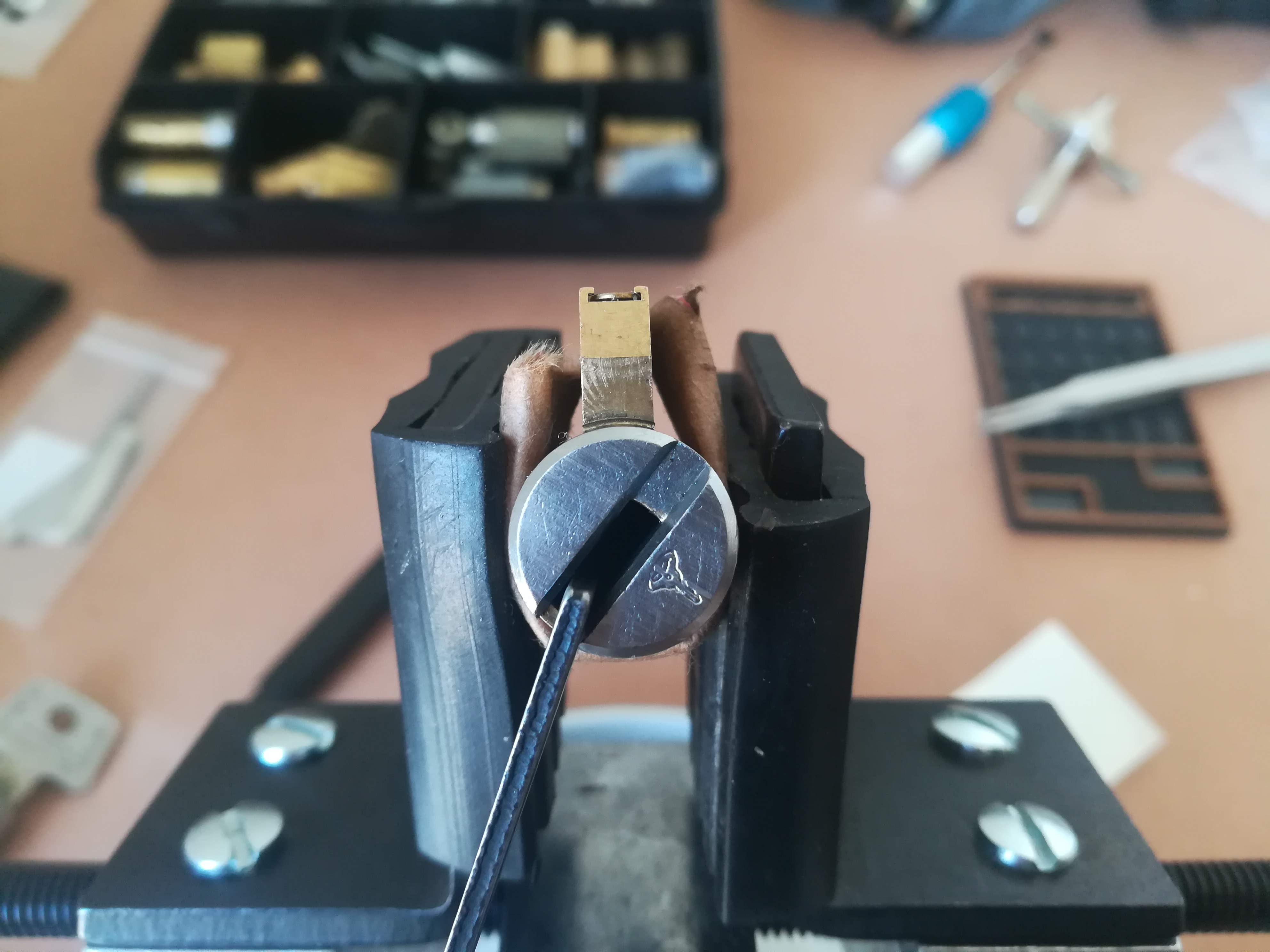 Photo of a Mul-T-Lock Interactive in a vise with a tension wrench hanging out of the keyway. The keyway has been rotated, showing that it has been picked.
